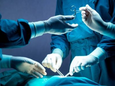 doctor and nurse medical team are performing surgical operation at emergency room in hospital. assistant hands out scissor and instruments to surgeons during operation.